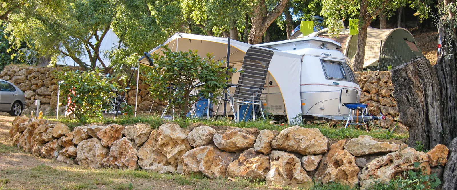Caravane et tentes installées sur les emplacements ombragés et les restanques du Camping Les Philippons
